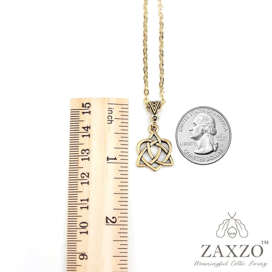 Gold sister knot charm necklace with trinity bail shown in between ruler and quarter.