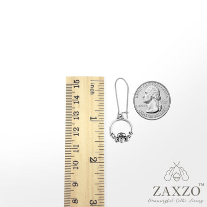 Silver Claddagh on sterling silver kidney wire between a ruler and quarter.