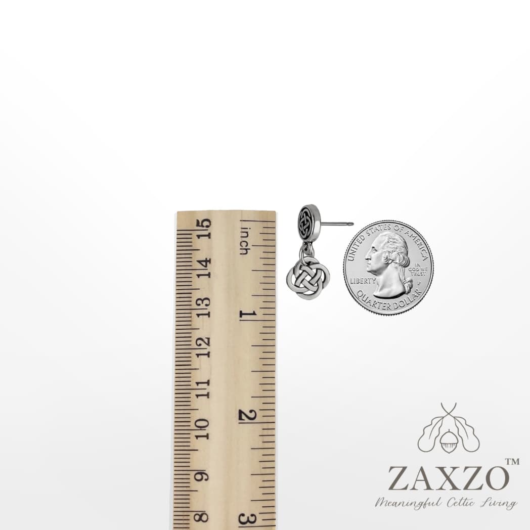Silver Dara knot with platinum post ear wire between a ruler and quarter.