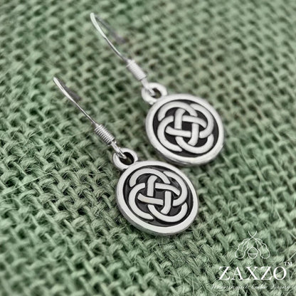Small Celtic silver Dara knot earrings with French sterling silver ear wire on green background.