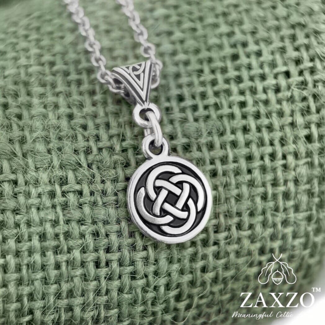 Small silver Celtic Dara knot necklace with trinity bail on green background.