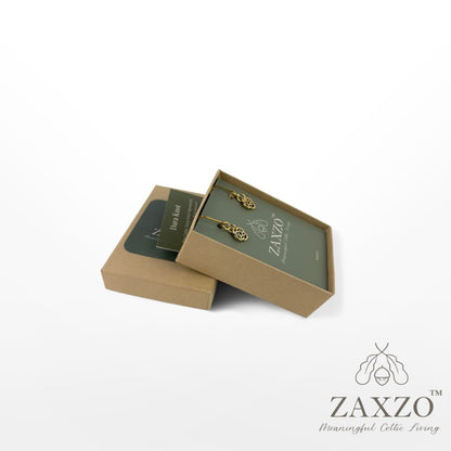 Tiny gold Dara knot platinum post earrings in open gift box with card explaining the meaning.